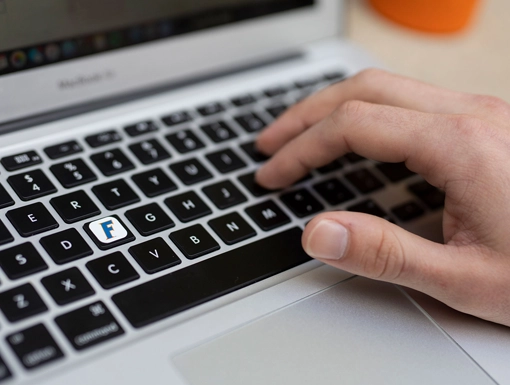 A person typing on a laptop keyboard with a stylized F